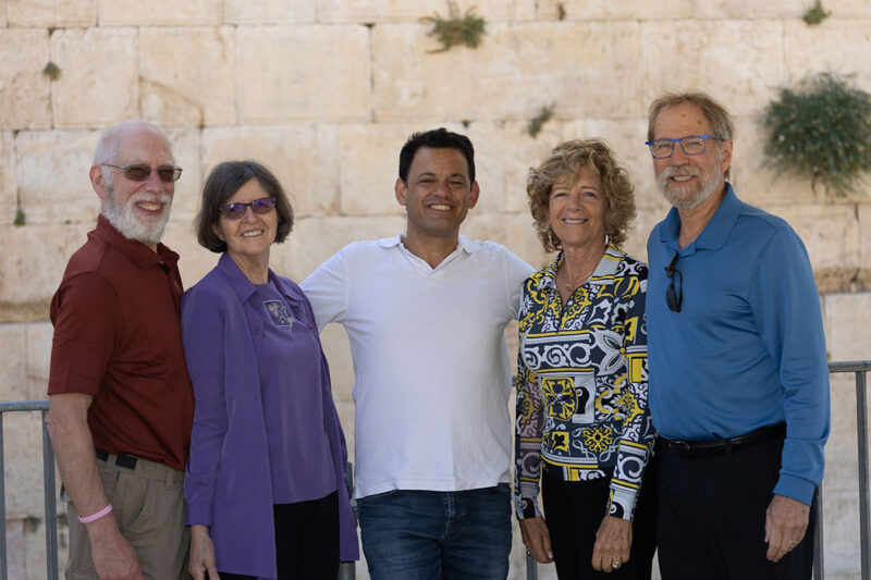 five people standing in front of the Western Wall in Jerusalem