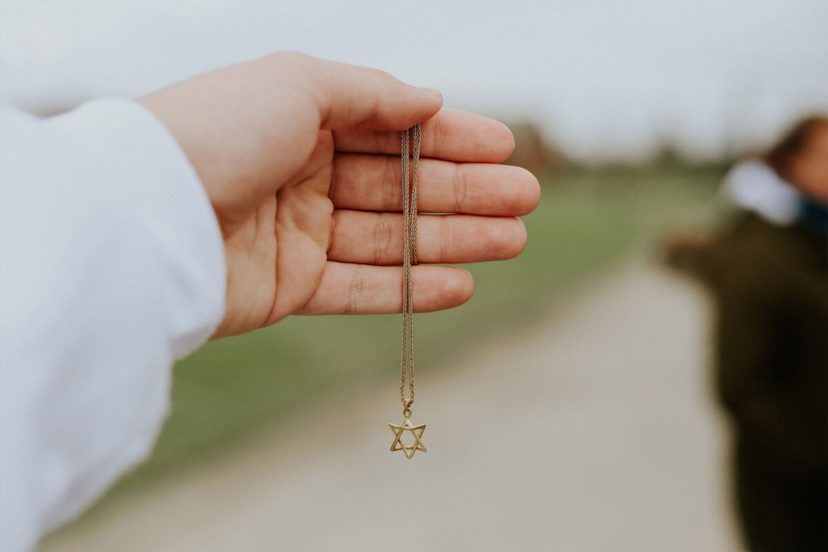 A hand holding a Star of David necklace