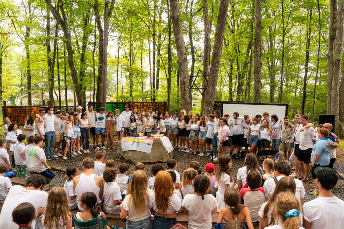 A large gathering of teens reading the Torah at camp